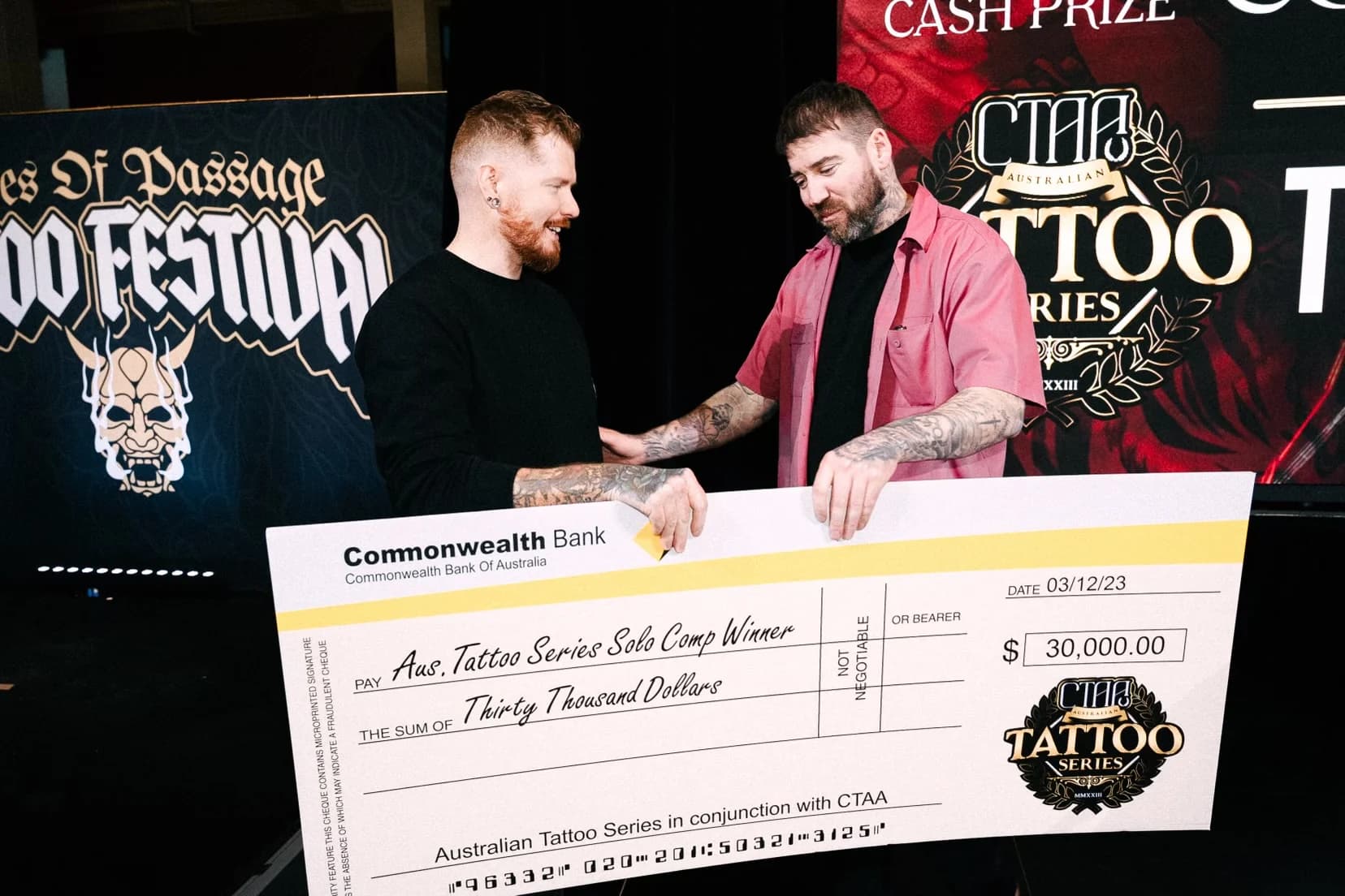 Kevin Mack handing a large $30,000 cheque to a winner on stage