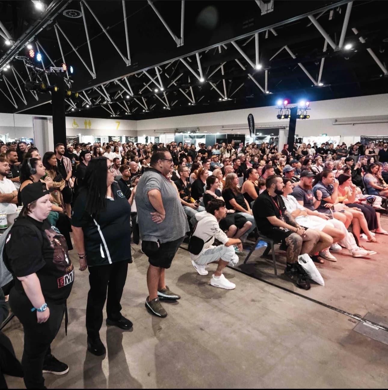 A seated crowd watching a stage at an exhibition