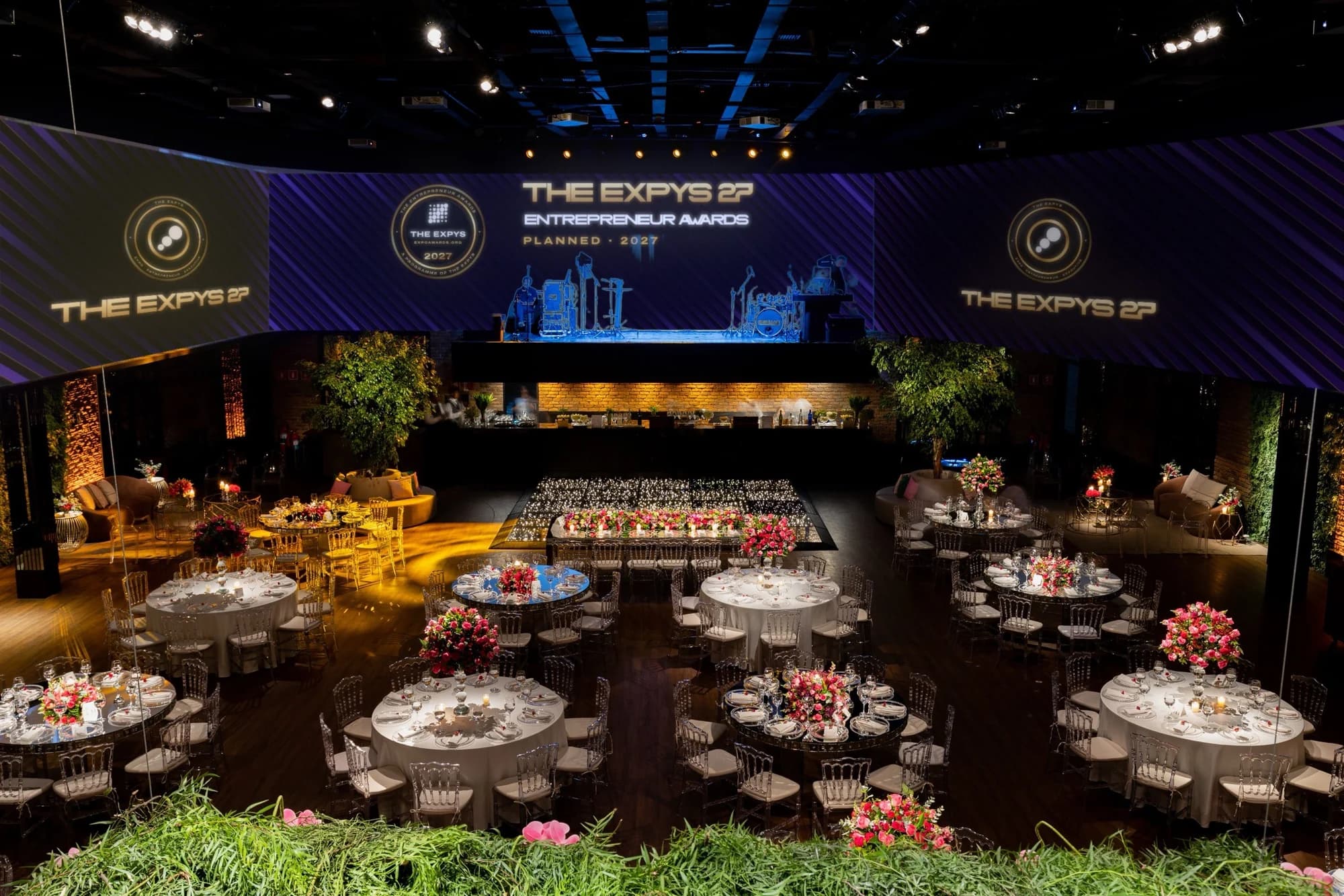 A garden room dressed for the Entrepreneur Awards with round tables and the stage