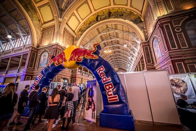 A Red Bull arch inside the Royal Exhibition Building with a crowd passing under it