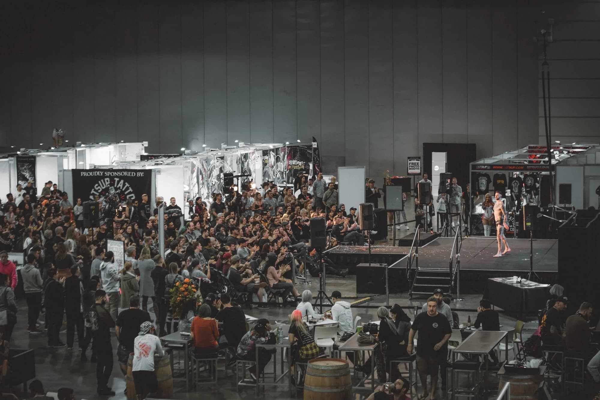 An exhibition hall seen from above, stands and crowd under the lights